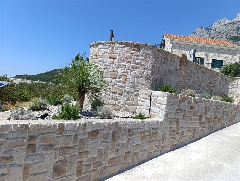 Uređen mediteranski vrt s kamenim suhozidom i palmom podno Biokova